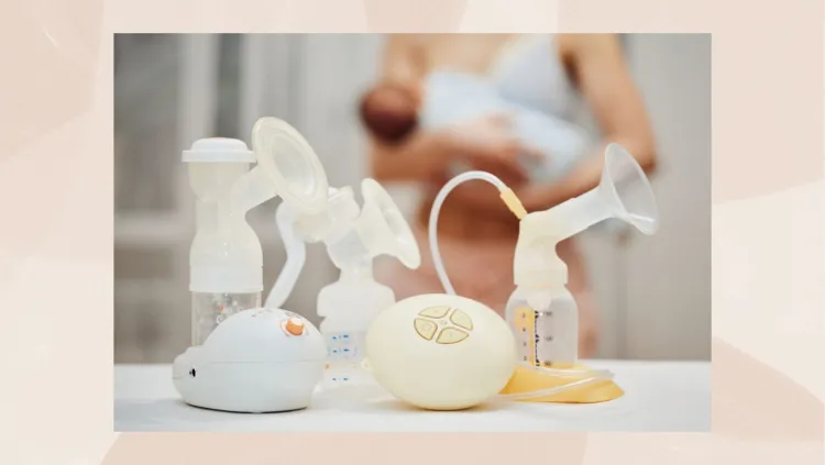 Various models of breast pumps are displayed on a surface with a blurred background showing a person holding a baby.